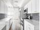 Bright kitchen featuring stainless steel appliances, gray subway tile backsplash, and white cabinets at 7877 E Mississippi Ave # 901, Denver, CO 80247