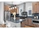 Modern kitchen features wood cabinets, stainless steel appliances, stylish lighting, and an island with seating at 9066 Harlan St, Westminster, CO 80031