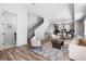 Open-concept living area with staircase, modern decor, wood floors, and views of the kitchen at 9066 Harlan St, Westminster, CO 80031