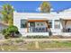 Charming bungalow featuring a white brick exterior, covered porch, and professionally landscaped front yard at 2327 Lowell Blvd, Denver, CO 80211