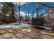 View of the backyard from the patio, featuring a trampoline, snow patches, and mature trees at 6941 S Poplar Way, Centennial, CO 80112