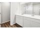 This bathroom features double sinks, white cabinets, and wood floors at 8807 Sedalia St, Commerce City, CO 80022