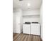 This laundry room includes modern machines, wood floors, and a shelf at 8807 Sedalia St, Commerce City, CO 80022