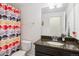 Bright bathroom featuring a granite countertop, stylish fixtures, and a colorful shower curtain at 11466 E 27Th Ave, Denver, CO 80238