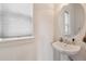 Bright powder room featuring stylish pedestal sink, neutral walls, and window for natural light at 11466 E 27Th Ave, Denver, CO 80238