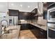A bright kitchen features stainless steel appliances, dark wood cabinetry and granite countertops at 11466 E 27Th Ave, Denver, CO 80238
