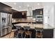 Modern kitchen features dark cabinets, granite island with seating, and stainless steel appliances at 11466 E 27Th Ave, Denver, CO 80238