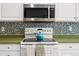 Kitchen features stove with kettle, overhead microwave, tile backsplash, and white cabinets at 1118 S Duquesne Cir, Aurora, CO 80018