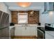 Well-lit kitchen with white cabinets, stainless steel appliances, quartz countertops, and exposed brick accents at 284 S Lafayette St, Denver, CO 80209