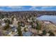 Neighborhood aerial view shows houses among mature trees near a lake under a partly cloudy sky at 8510 Independence Way, Arvada, CO 80005