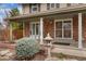 Inviting covered porch with brick detail, decorative shrubbery, and secure screen door at 8510 Independence Way, Arvada, CO 80005