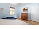 Calm bedroom featuring light blue walls, hardwood floors, and a wood dresser with art above at 1842 S Fairfax St, Denver, CO 80222