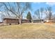 Expansive backyard with a brick home, green lawn, mature trees, and an enclosed patio at 3276 S Osceola St, Denver, CO 80236