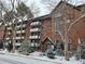 A brick apartment building with balconies and snow-covered landscaping at 1270 N Marion St # 103, Denver, CO 80218