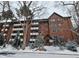 Charming brick condo building featuring multiple balconies and snow-covered landscaping at 1270 N Marion St # 103, Denver, CO 80218