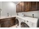 Functional laundry room with modern washer and dryer, ample storage, and a utility sink at 13942 W 87Th Dr, Arvada, CO 80005