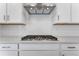 Close-up of a modern stovetop range with custom hood and white subway tile backsplash at 16517 W 92Nd Pl, Arvada, CO 80007