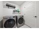 Well-lit laundry room featuring a washer and dryer set, shelving, and a white door at 10224 Worchester St, Commerce City, CO 80022