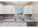 Bright kitchen features white cabinets, stainless steel sink, and gray countertops at 1522 Chimney Peak Dr, Castle Rock, CO 80109