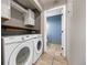 Functional laundry room with washer, dryer, storage cabinets, and blue accent bathroom at 1522 Chimney Peak Dr, Castle Rock, CO 80109