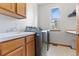 Bright laundry room with modern washer and dryer, wooden cabinets, sink and window at 31042 Wildwoods, Evergreen, CO 80439