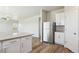 Open-concept kitchen with stainless steel refrigerator, white cabinetry, and a breakfast bar overlooking the living area at 48255 Shetland Dr, Bennett, CO 80102