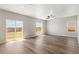 Spacious living room with wood flooring, ample natural light from large windows, and a sliding glass door to the yard at 48255 Shetland Dr, Bennett, CO 80102