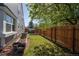 Backyard featuring a wooden fence, garden beds, lawn, and mature trees, ideal for relaxation and gardening at 87 Macon Ct, Aurora, CO 80010
