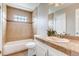 Cozy bathroom featuring a vanity, tub with tile, and a unique glass block window for natural light at 87 Macon Ct, Aurora, CO 80010