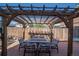 Patio featuring a wooden pergola with string lights, dining table, and chairs, creating a cozy outdoor space at 87 Macon Ct, Aurora, CO 80010