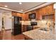 Kitchen featuring wood cabinets, granite countertops, and a complete black appliance set at 3131 E Alameda Ave # 704, Denver, CO 80209