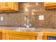 Close up of stainless steel sink with granite counter tops and dark backsplash at 3221 Autumn Sun Cir, Castle Rock, CO 80104