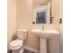 Cozy half bathroom with white toilet and pedestal sink and a view of the staircase at 9605 Elk Mountain Cir, Littleton, CO 80125