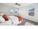 Bright bedroom with three windows, ceiling fan, carpet, and bed with white linens and coral throw blanket at 1665 Diamond Head Dr, Castle Rock, CO 80104