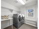 Well-lit laundry room featuring modern washer and dryer, white shelving, and a convenient folding table at 1665 Diamond Head Dr, Castle Rock, CO 80104