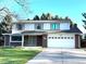 Charming two-story home with a well-maintained lawn, a two-car garage, and mature trees in the background at 4640 W Princeton Ave, Denver, CO 80236