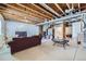Unfinished basement with open ceiling, concrete floor, couch, and access to the stairs at 10991 Xanadu St, Commerce City, CO 80022