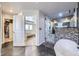 This renovated bathroom features a stand alone tub and glass shower adjacent to the primary bedroom at 10991 Xanadu St, Commerce City, CO 80022