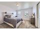 Cozy bedroom with a rustic wood accent headboard, plush gray bedding, and two sunny windows at 10991 Xanadu St, Commerce City, CO 80022