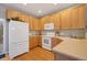 Well-lit kitchen with wooden cabinets, white appliances, and hardwood floors at 4357 W 118Th Pl, Westminster, CO 80031