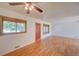 Bright living room featuring beautiful hardwood floors, large windows, and a classic ceiling fan at 6054 Iris Way, Arvada, CO 80004