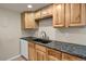Kitchen featuring wooden cabinets, dark countertops, undermount sink, and white dishwasher at 3675 S Cherokee St # 110, Englewood, CO 80110