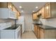 A bright kitchen featuring white appliances, wooden cabinets, dark countertops, and tile flooring at 3675 S Cherokee St # 110, Englewood, CO 80110