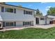 Back exterior with a large grassy area, light siding, dark shutters, and a concrete patio at 2554 S Laredo Ct, Aurora, CO 80013