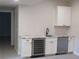 Basement bar area with a sink, wine cooler, white cabinets, and modern finishes at 1970 S Logan St, Denver, CO 80210