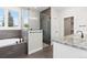 Bright bathroom featuring a soaking tub with shower, a glass shower, and neutral tile at 1970 S Logan St, Denver, CO 80210