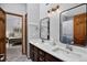 Bright bathroom featuring double sinks, wood cabinets, and an adjoining doorway to the bedroom at 31258 Niakwa Rd, Evergreen, CO 80439