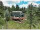 Spacious two-story home featuring a large deck and surrounded by towering trees on a lush green lawn at 31258 Niakwa Rd, Evergreen, CO 80439