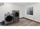 Laundry room features modern washer and dryer, wood look flooring, and window for natural light at 10343 Stoneflower Dr, Parker, CO 80134