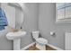Bright powder room features pedestal sink, oval mirror, wood floors and neutral paint at 23913 E Swallow Cir, Aurora, CO 80016